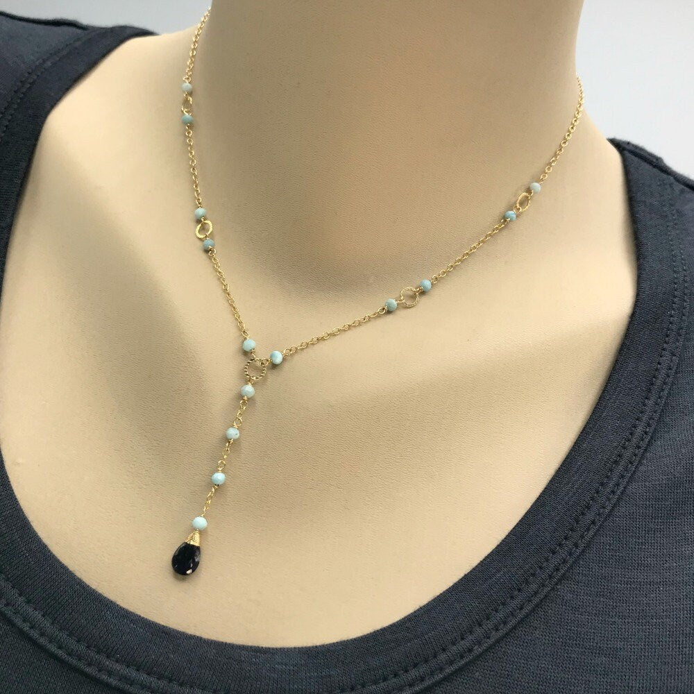 This handcrafted blue Y necklace features a stunning combination of faceted Iolite and smooth Larimar, creating a delicate yet bold design. The tear drop Iolite stone, paired with soft, cloud-blue Larimar rondelles, provides a beautiful contrast that adds a touch of elegance to any outfit. Perfect for layering, this dainty necklace is ideal for casual or dressy looks. Its soothing colors are not only eye-catching but also offer healing properties, making it a thoughtful gift for any occasion.
