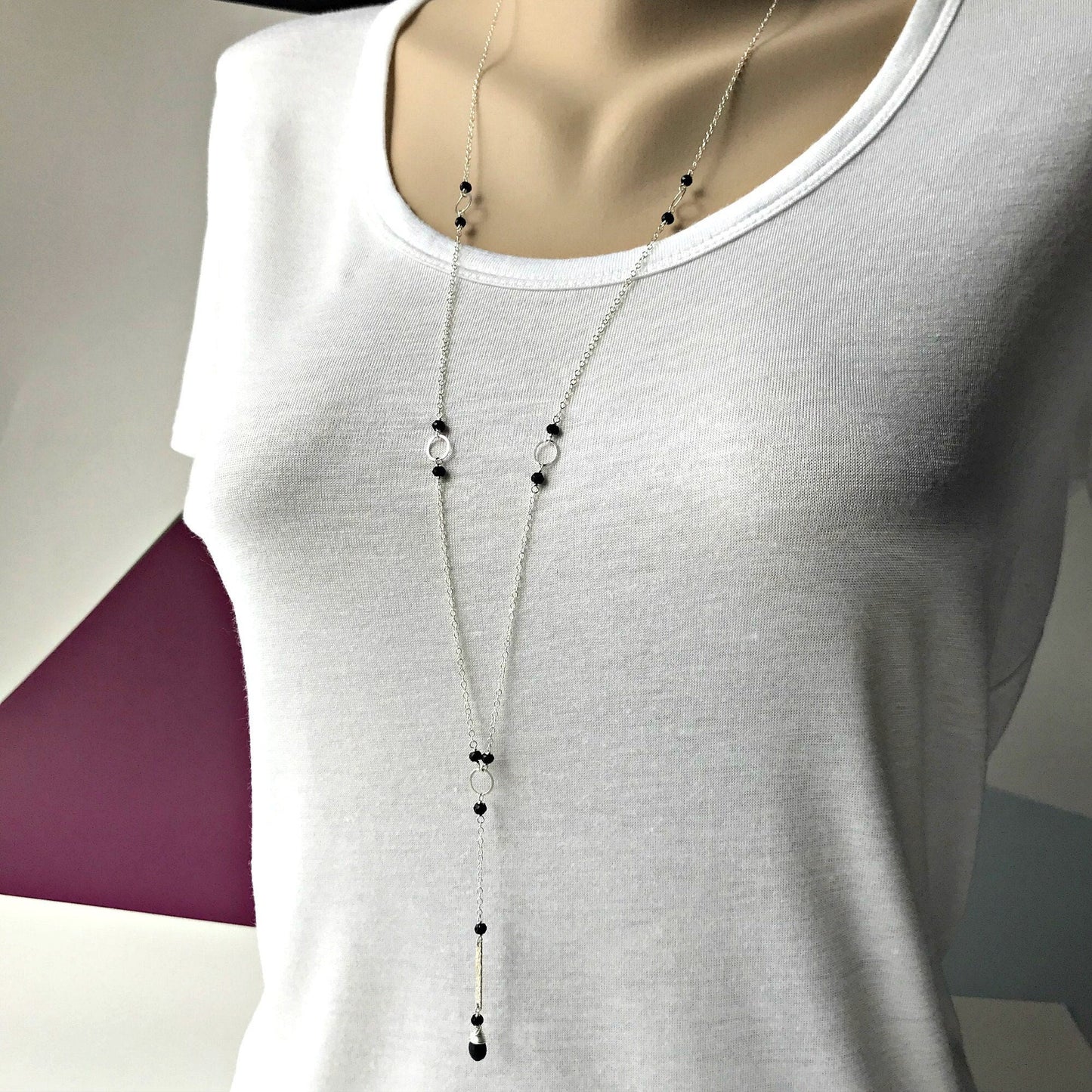 The Elegant Black Spinel Y Necklace beautifully combines minimalist design with timeless appeal. It features delicate, faceted black spinel beads interspersed with gold rings along a lightweight gold or silver chain. This necklace creates a sophisticated Y-shaped drop that gracefully accentuates your neckline. It’s perfect for everyday wear or layering, complementing any outfit with ease.