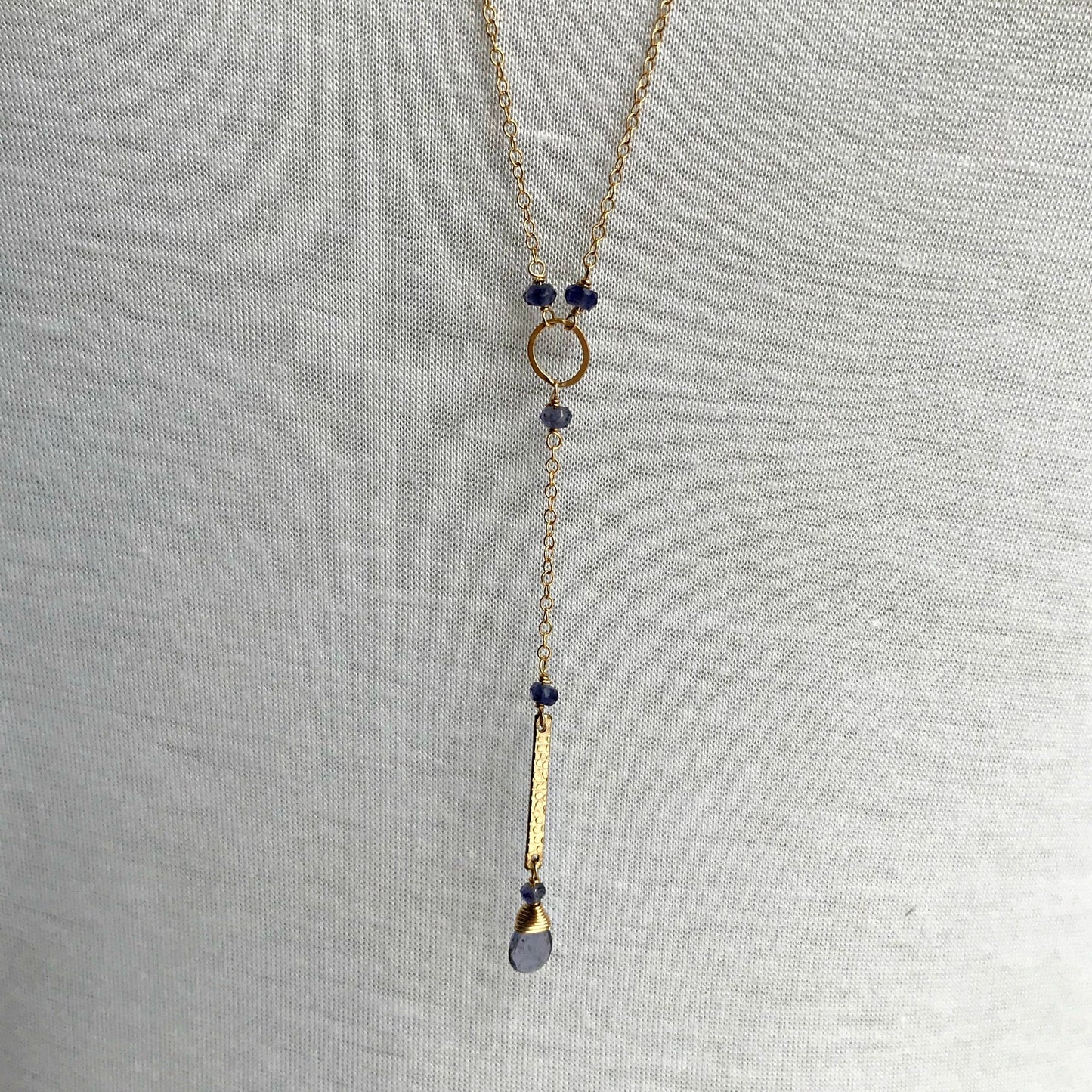 Close-up of Iolite Y Necklace featuring a dainty gemstone drop and textured bar in gold, showcasing its elegant design and fine details.