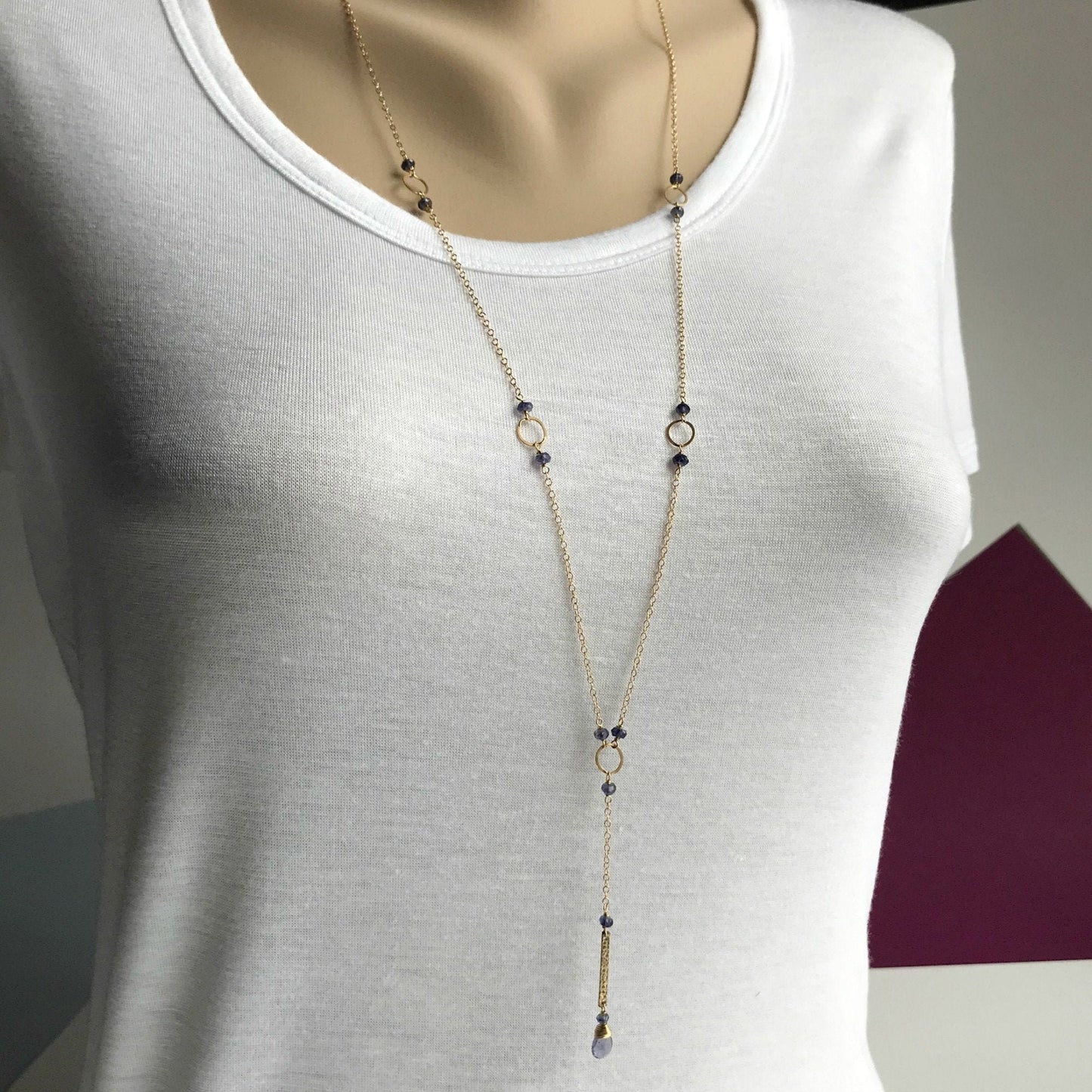 This delicate Iolite Y Necklace is designed to capture attention and add a touch of elegance to any outfit. Carefully arranged Iolite beads are paired with minimalist gold rings, creating a stunning contrast along an airy gold chain. The "Y" drop gracefully falls to the perfect point, beautifully accentuating your décolletage.